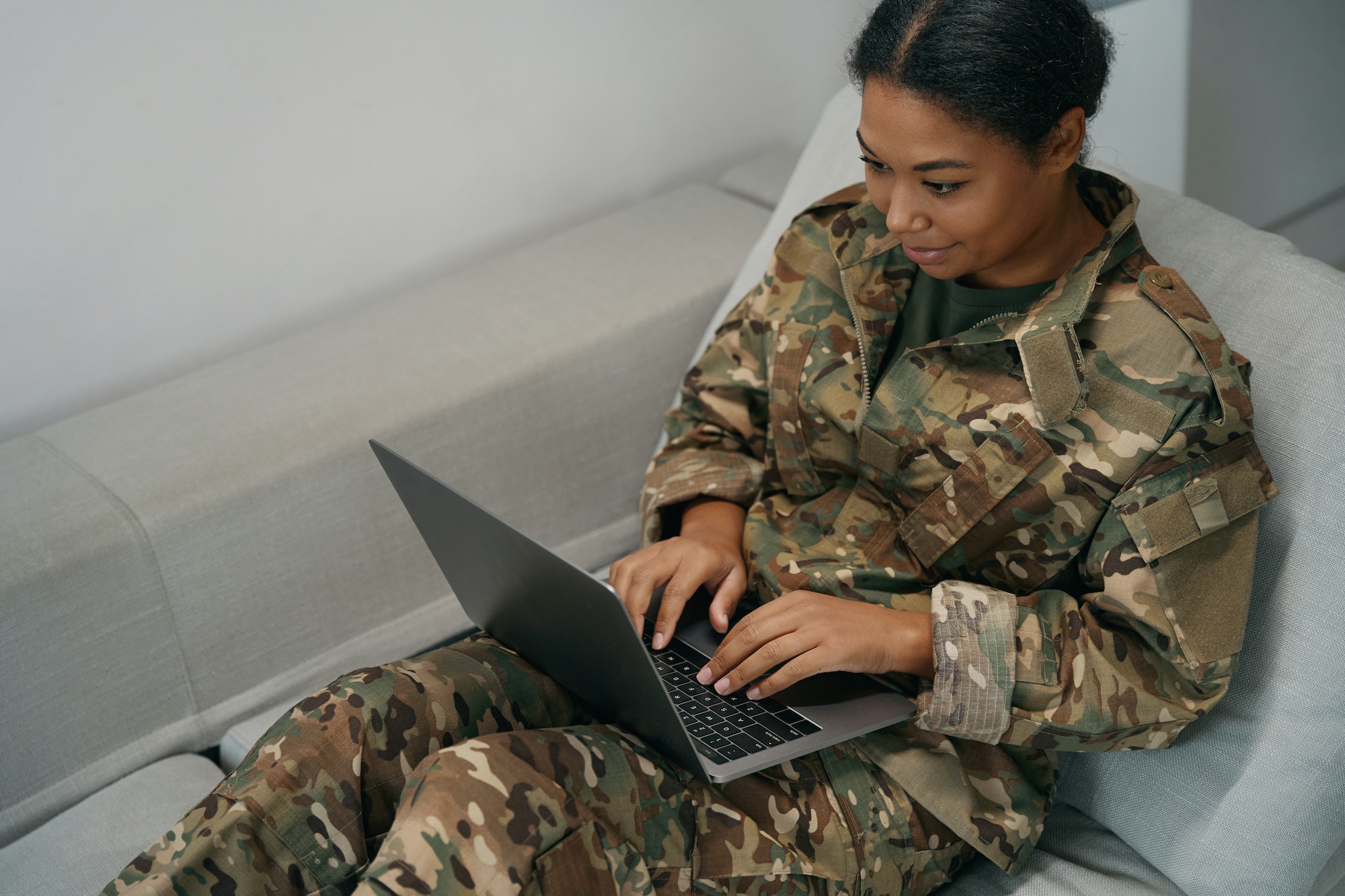 Cute female soldier is typing something in a laptop